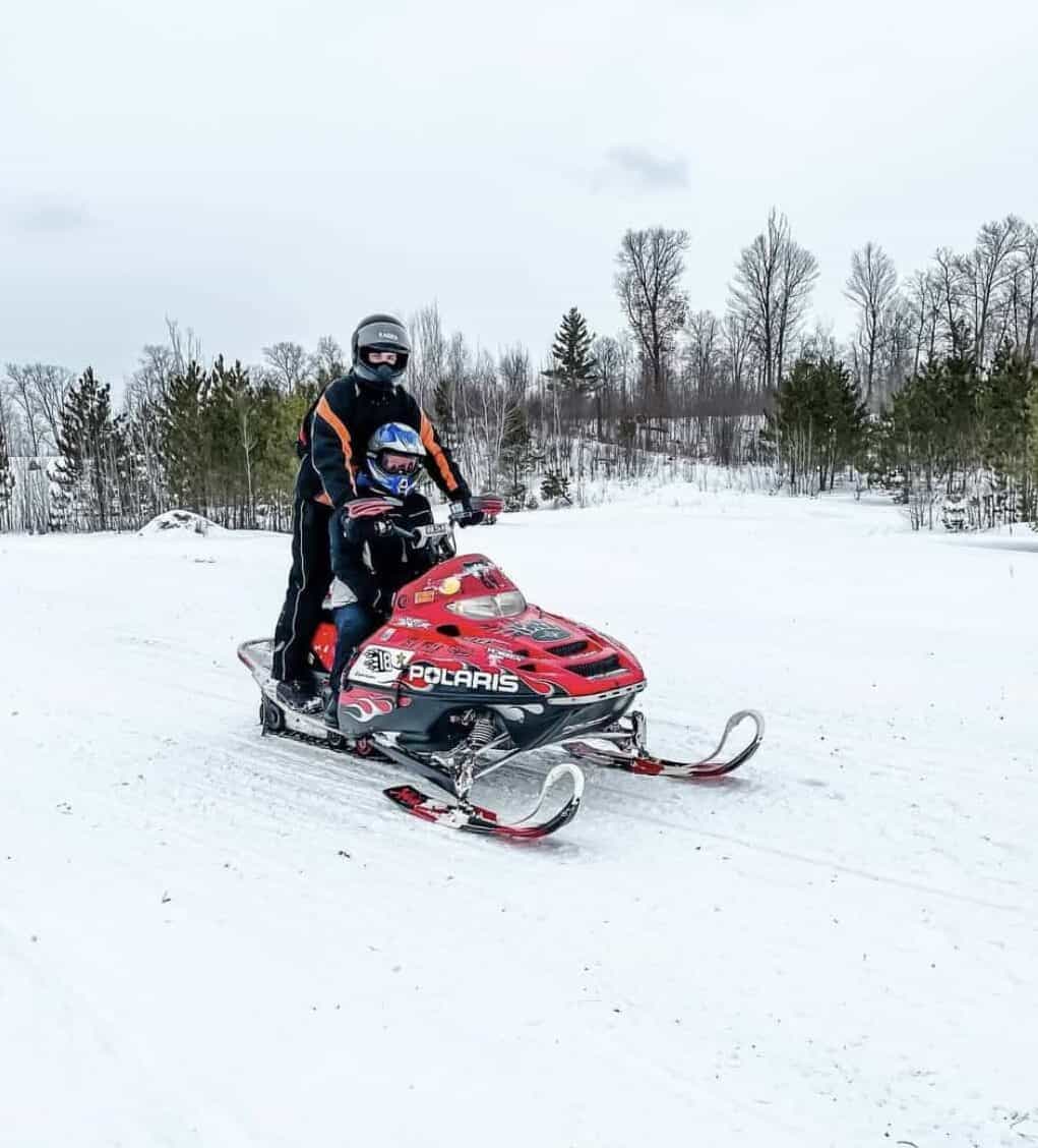 Myself and Tyler on a red snowmobile during the winter month in Minnesota.