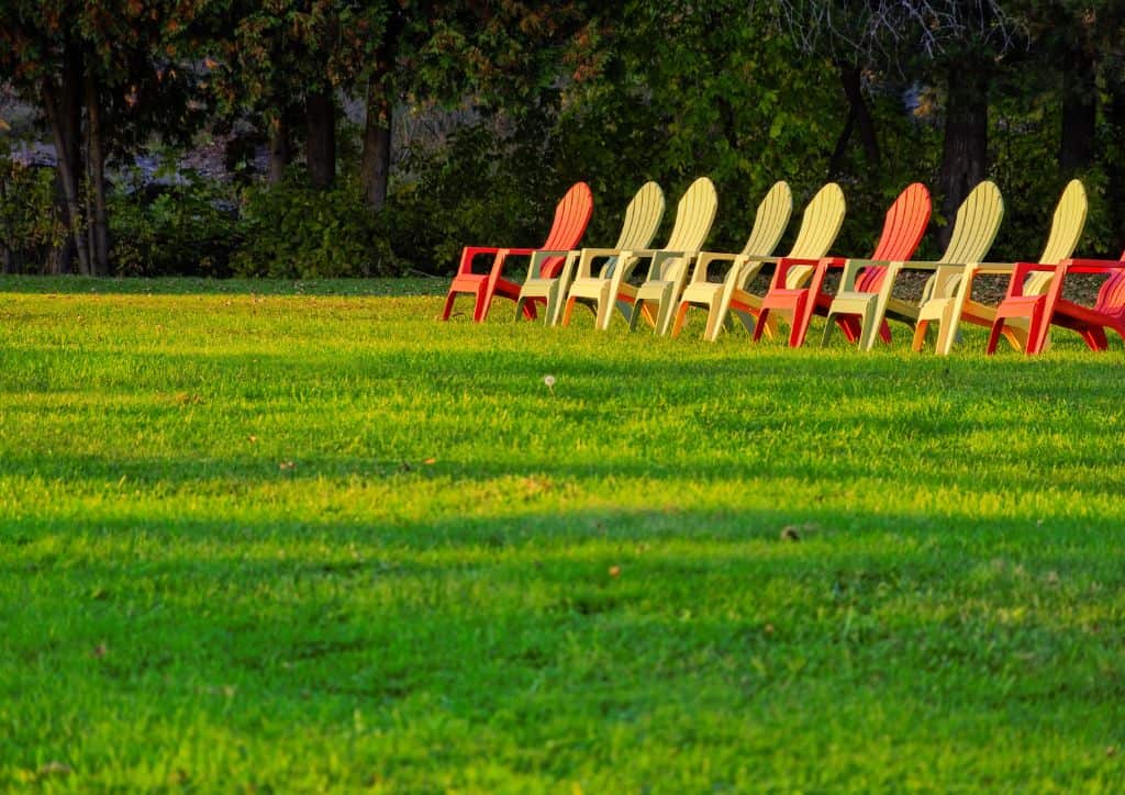 Lawn chairs on a large grass area at a resort.