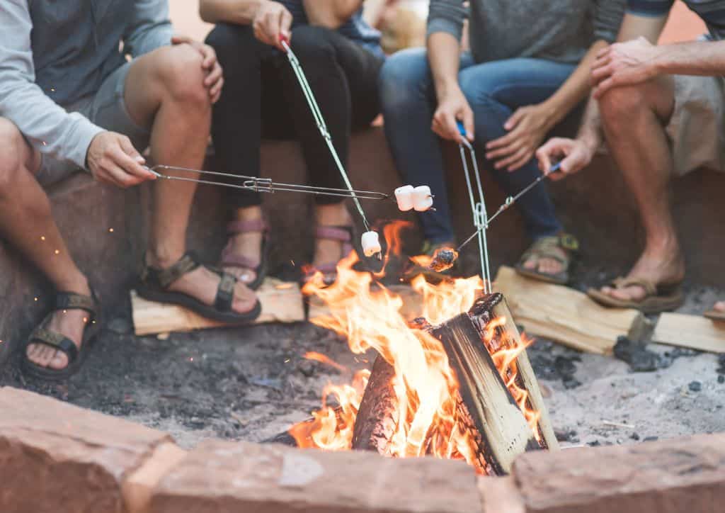 Friends sitting around a bonfire making s'mores.