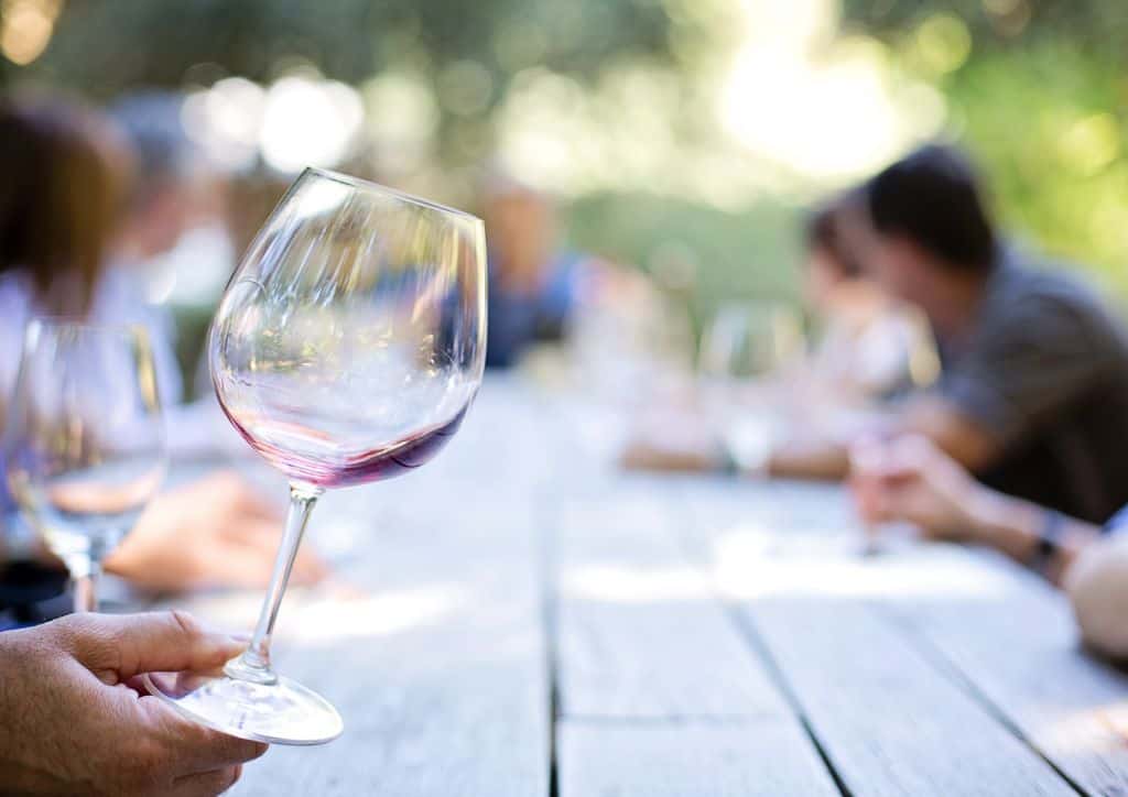 An empty wine glass on a picnic table.