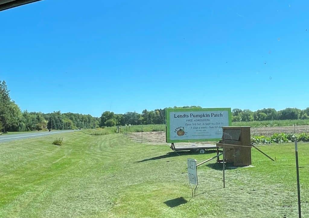 A sign leading guests into Lendt's Pumpkin Patch, sitting next to a large field.