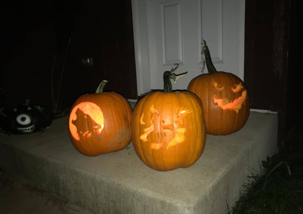 Three Jack-O-Lanterns sitting on the front step of a house.