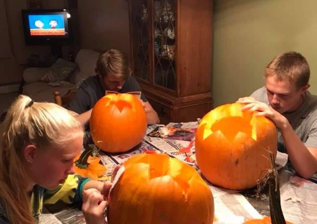 Myself, my brother, and my boyfriend carving pumpkins at the kitchen table of my home.