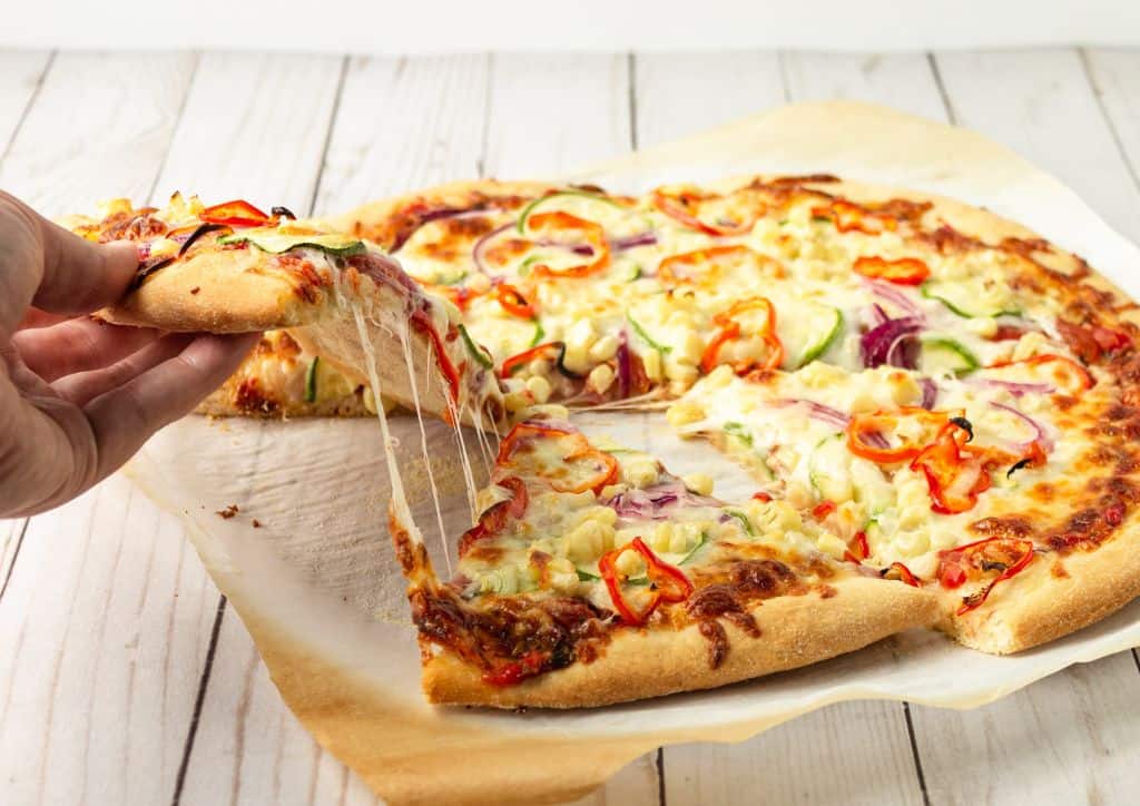 A person grabbing a piece of pizza.