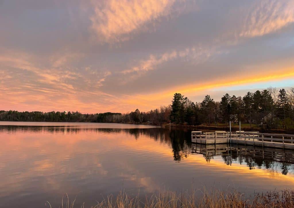 A view of sunset at a lake in Minnesota with a dock in it.