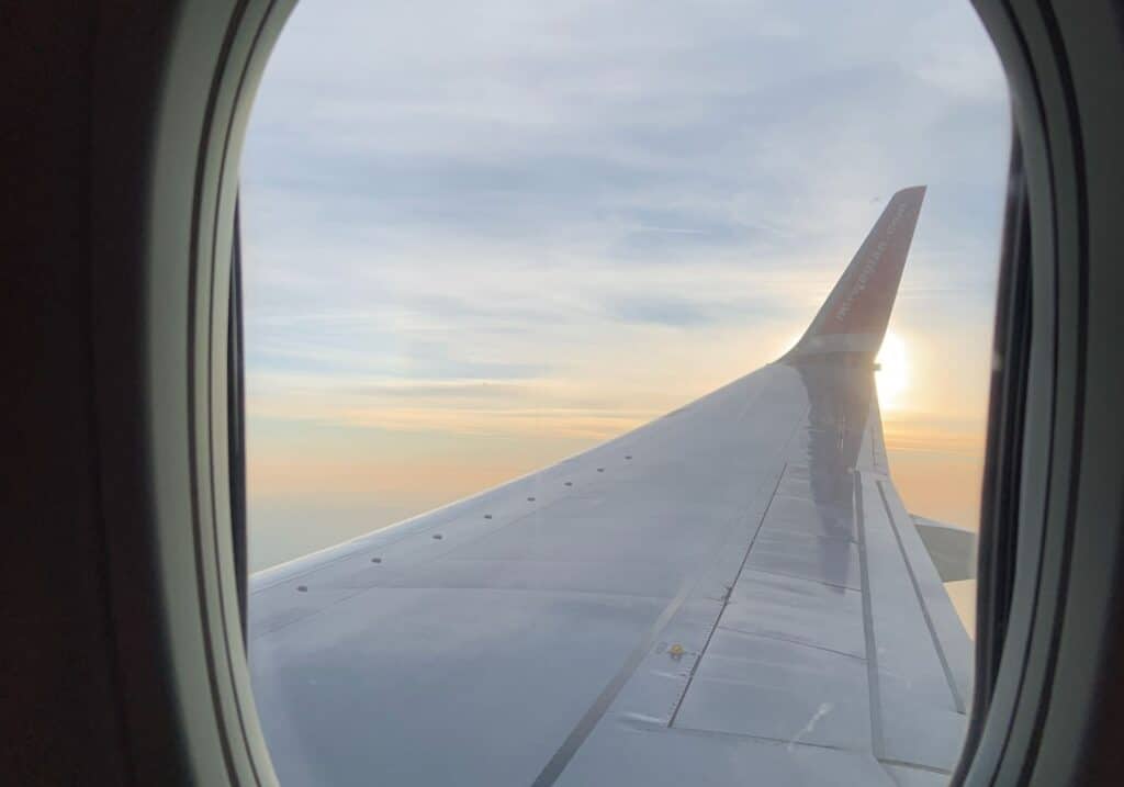 A view of a plane wing outside of the plane in the air.
