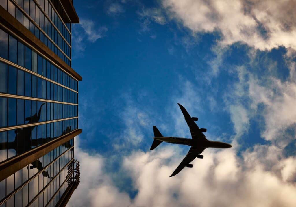A plane flying overhead near a building.