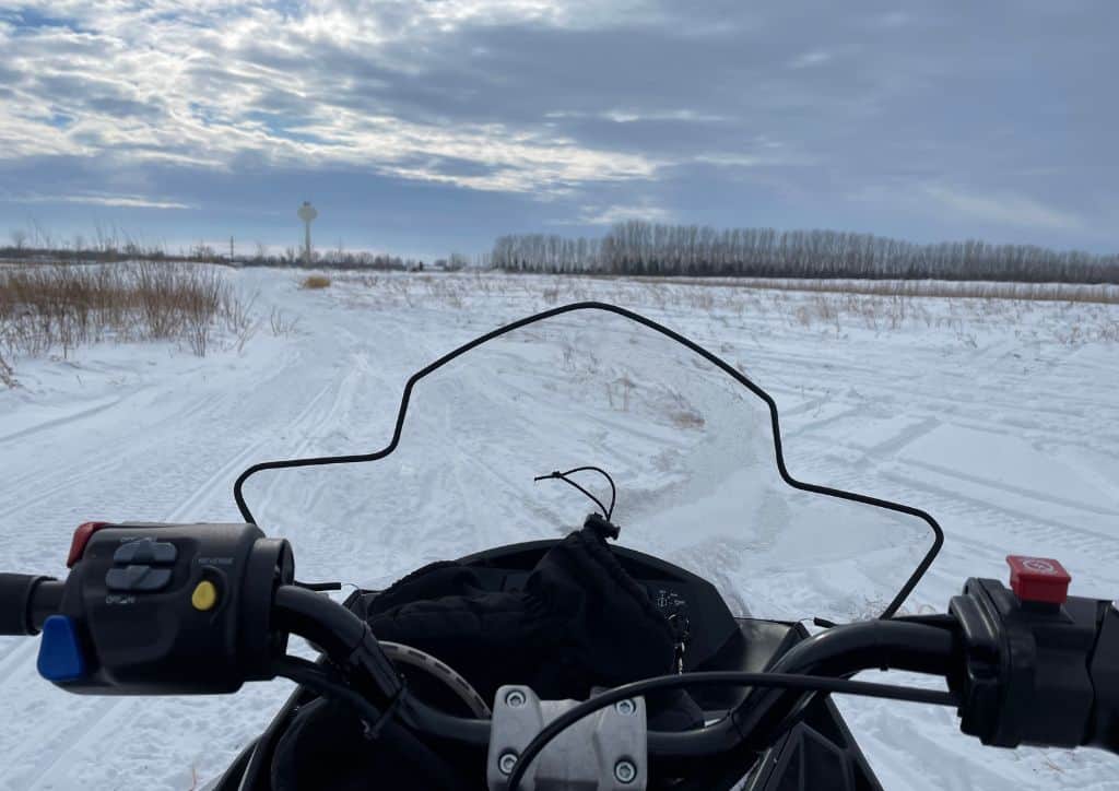 The handles of a snowmobile in a field.