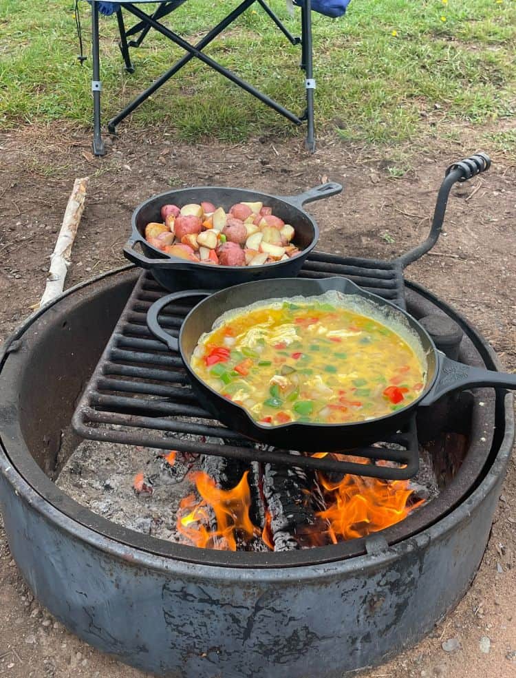 Two pans cooking over a bonfire while camping in Southern Minnesota.