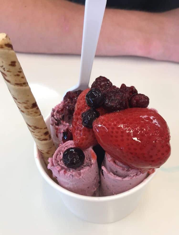 A cup of rolled ice cream with berries on top.