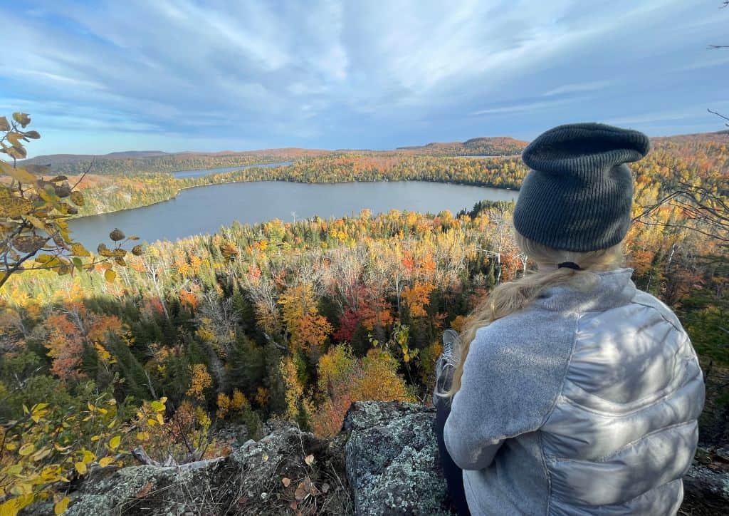 Myself sitting on a rock overlooking a lake and fall foliage.