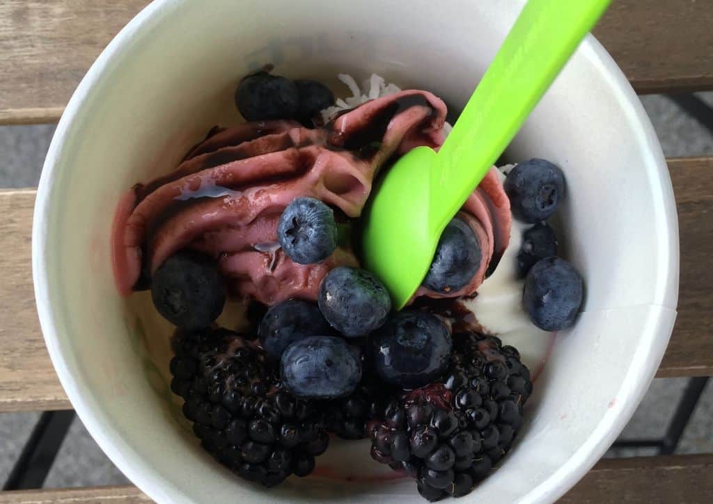 A cup of frozen yogurt with berries as toppings.