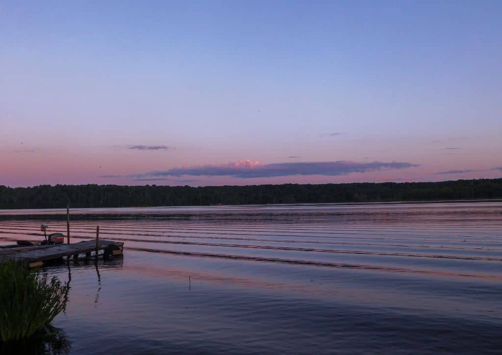 A lake at sunset with a dock in the water.