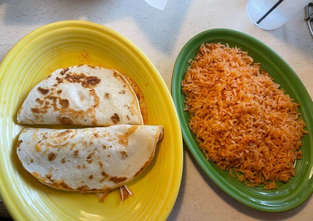 Quesadillas and rice on colorful plates.