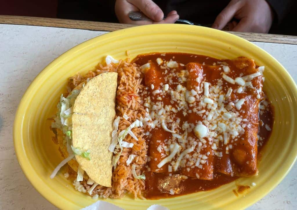 Enchiladas and a taco on a yellow plate.