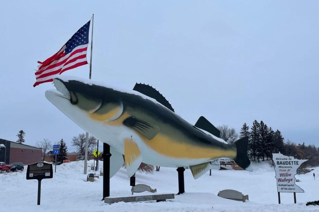 A giant yellow and green walleye statue near Lake of the Woods with a sign that reads "Welcome to Baudette."