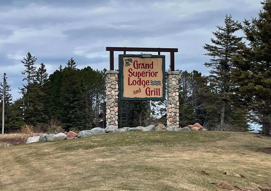 The wooden sign at the entrance of Grand Superior Lodge, with stone pillars around it.